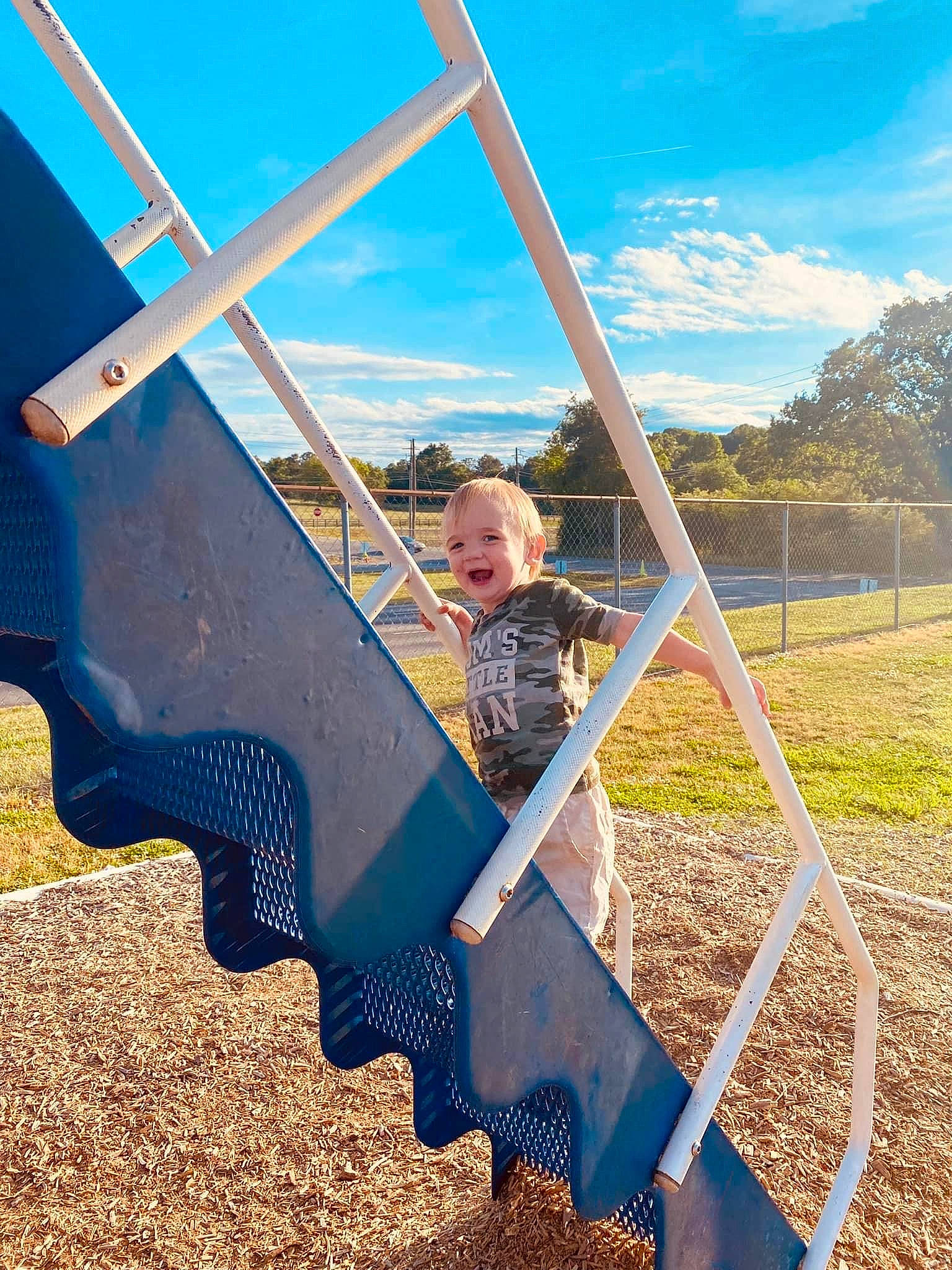 Wyatt joined the competition — help win amazing prizes! city, cloud, fun, grass, grassland, joy, landscape, leisure, outdoor_play_equipment, person, plant, pole, recreation, shadow, sky, soil, stairs, swing, t_shirt, toddler