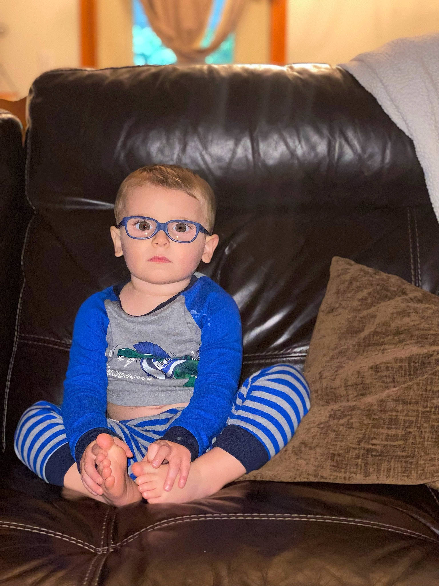 Theodore is registered to the contest to win money with this photo: baby_toddler_clothing, blue, comfort, couch, electric_blue, eyewear, facial_expression, flash_photography, flooring, fun, furniture, goggles, hair, hairstyle, lap, leisure, living_room, person, sitting, toddler