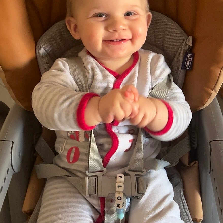 Maylon participe au concours pour gagner de l'argent avec cette photo : baby, blond_hair, buckle, car_seat_style, chicco_logo, clasped_hands, closeup, happy_expression, high_chair, indoors, infant, onesie, pacifier_clip, portrait, red_trim, rosy_cheeks, safety_harness, seat_cushion, smiling, striped_pajamas