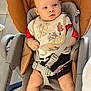 baby, infant, stroller, car_seat, bib, harness, buckle, seat, chubby_legs, bare_foot, face, eyes, looking, indoor, tiled_floor, baby_clothes, red_shirt, beige_seat, chicco_brand, baby_bouncer