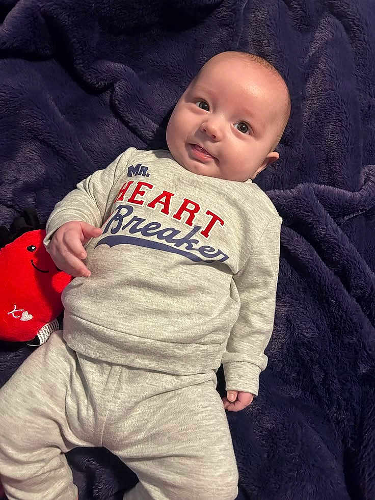 Myles joined the competition — help win amazing prizes! baby, infant, smile, blanket, pajamas, plush_toy, toy, face, portrait, eyes, hand, cute, cozy, soft_texture, home_interior, lying_down, clothing, bald, happy, photography