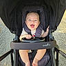 Waylen is registered to the contest to win money with this photo: baby, stroller, smile, happy, child, infant, outdoor, sunlight, seatbelt, hand, foot, clothing, person, transport, baby_stroller, black, pavement, daylight, cute, safety