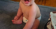 Waylen joined the competition — help win amazing prizes! baby, child, smiling, happy, sitting, diaper, indoor, floor, rug, bag, football_pattern, cute, infant, skin, face, hand, foot, wooden_floor, couch, expression