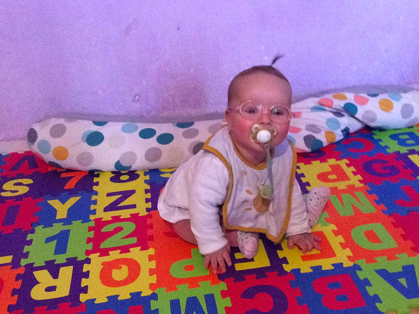 Zohra a rejoint le concours — aidez-le/la à gagner de superbes lots ! baby, baby_products, baby_toddler_clothing, bedtime, child, comfort, crawling, floor, flooring, fun, happy, linens, pattern, person, play, playmat, room, sitting, sleeve, toddler