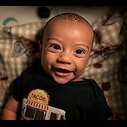 Keaton joined the competition — help win amazing prizes! baby, smiling, face, child, black_shirt, taco, patterned_blanket, happy, portrait, indoors, cute, infant, closeup, young_child, head, eyes, mouth, toddler, clothing, person