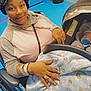 woman, baby, wheelchair, car_seat, blanket, hospital_bracelet, floor, blue_floor, indoor, smile, hand, ring, hoodie, pacifier, newborn, child, person, medical, seat, cozy