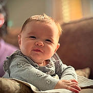 Autumn is registered to the contest to win money with this photo: baby, infant, child, face, portrait, smile, clothing, flower_pattern, hand, couch, blanket, soft_light, indoors, cozy, cute, young_child, resting, warm_tone, expression, sitting