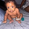 baby, child, infant, pacifier, bed, blanket, person, curly_hair, skin, hand, foot, sitting, indoors, casual, clothing, expression, wide_eyes, diaper, background, lighting