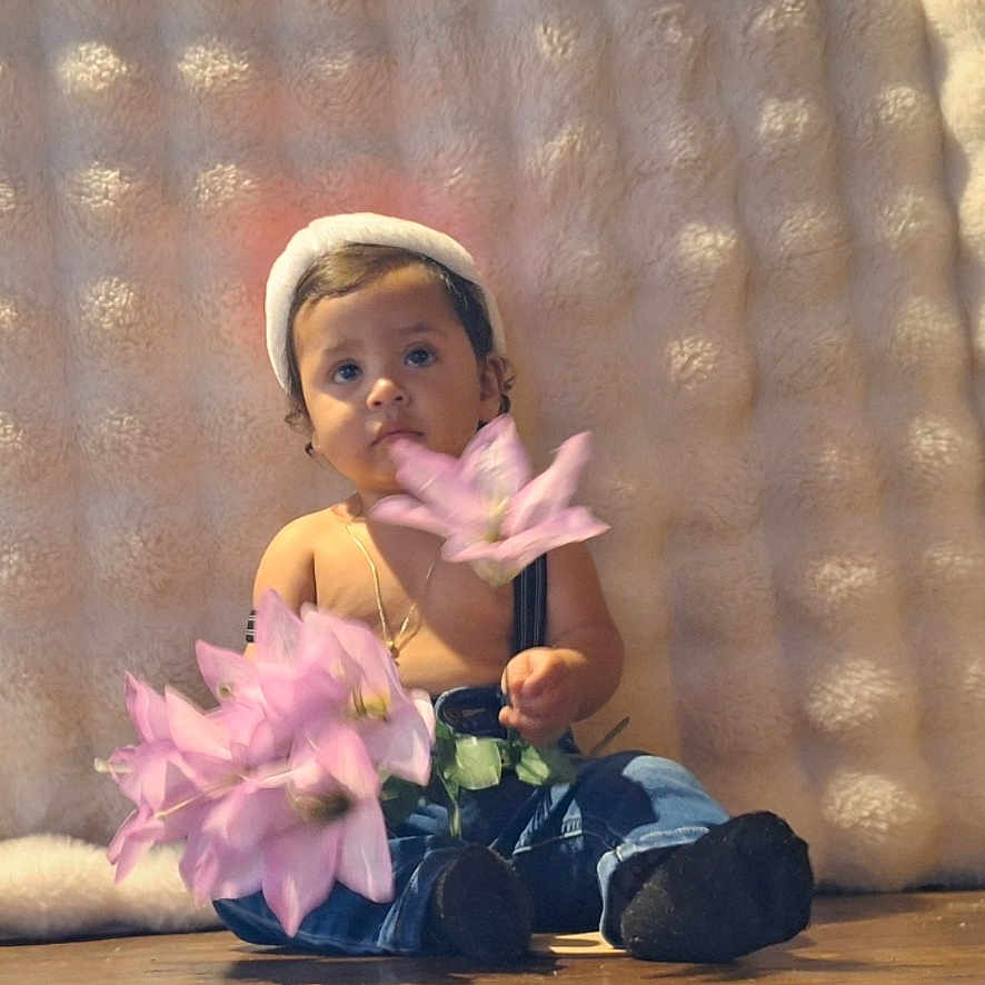 Karim Gomez joined the competition — help win amazing prizes! baby, black_socks, casual_clothing, child, cozy_background, curious_expression, cute, flower, hat, indoors, innocent, jeans, person, pink_flower, portrait, sitting, soft_texture, suspenders, toddler, wooden_floor