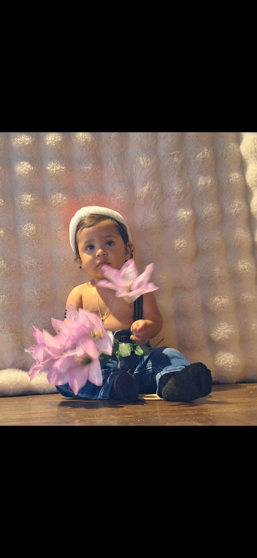 Karim Gomez joined the competition — help win amazing prizes! toddler, child, flower, pink_flower, hat, suspenders, jeans, black_socks, wooden_floor, cozy_background, curious_expression, indoors, portrait, cute, baby, sitting, soft_texture, innocent, person, casual_clothing