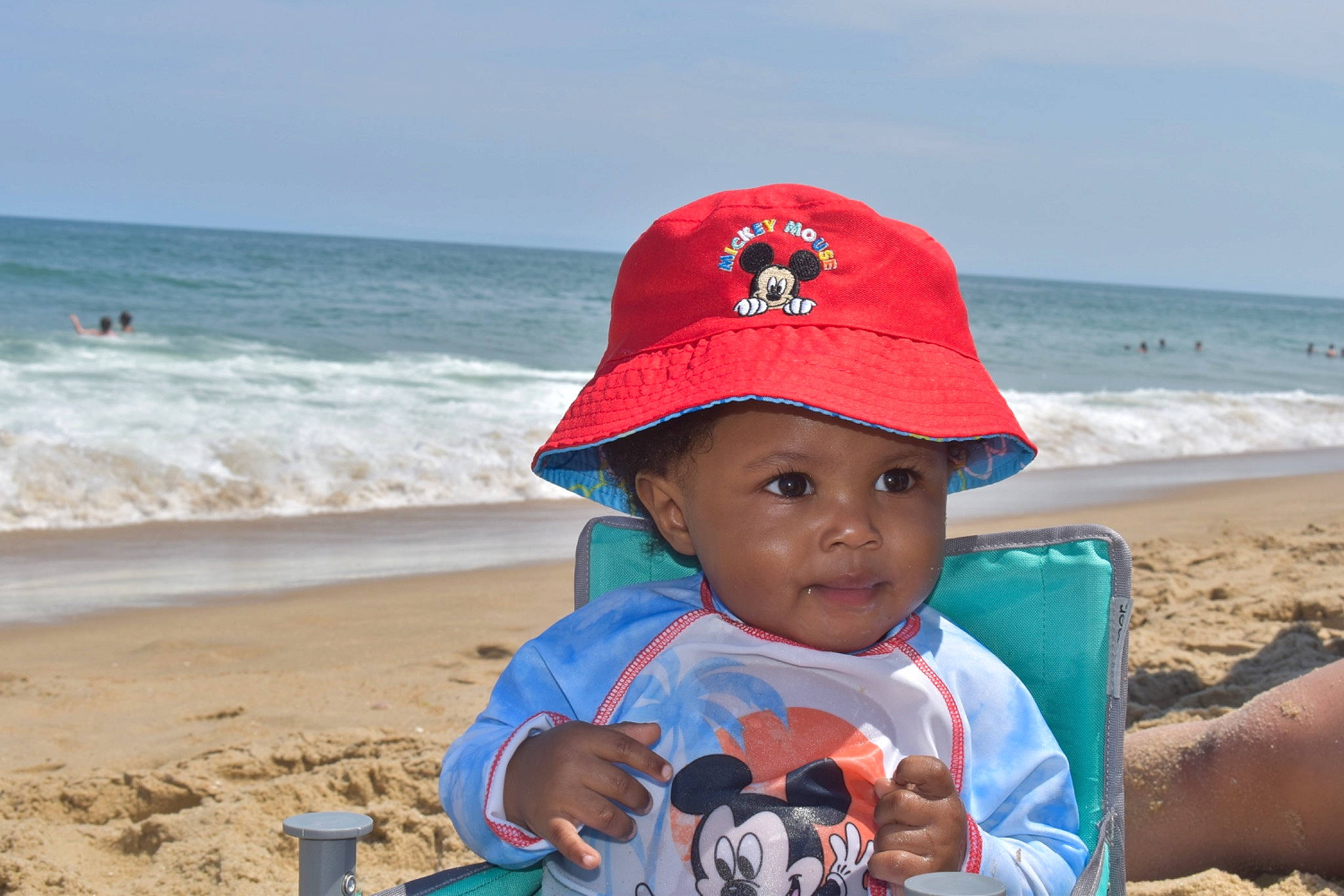 Landyn is registered to the contest to win money with this photo: azure, beach, cap, fashion_accessory, fun, happy, hat, headgear, headwear, holiday, leisure, natural_environment, people_on_beach, person, personal_protective_equipment, photograph, sand, sky, summer, toddler