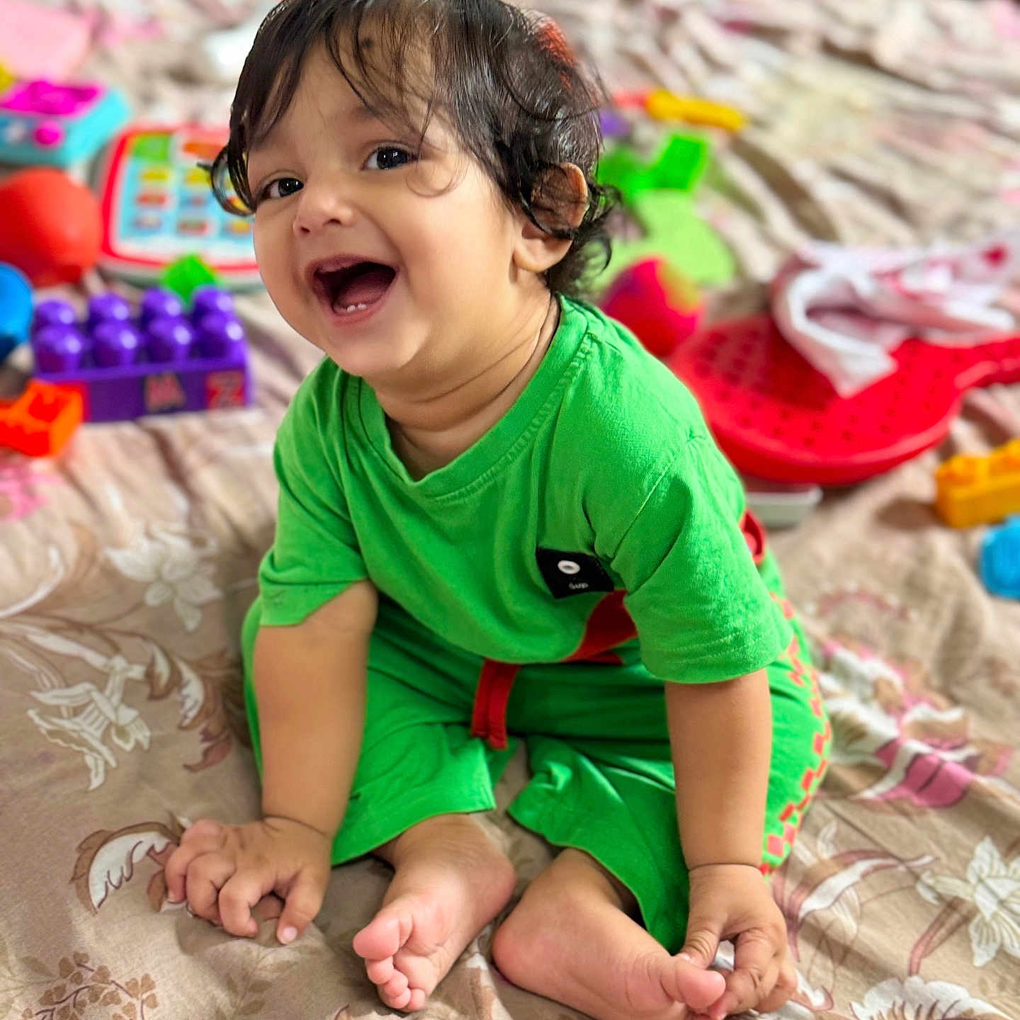 Samridh joined the competition — help win amazing prizes! baby, background_blur, bedspread, bright_colors, child, cute, face, feet, green_clothing, hair, hands, happy, indoors, playing, portrait, sitting, smiling, toddler, toys, young_child