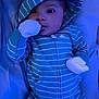 baby, infant, onesie, hood, striped_clothing, blue_color, mittens, lying_down, blanket, soft_fabric, closeup, face, cute, child, sleepwear, indoors, portrait, baby_clothes, young_child, calm