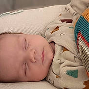 Milo participe au concours pour gagner de l'argent avec cette photo : baby, sleeping, blanket, cozy, patterned_clothing, infant, soft_texture, resting, peaceful, face, head, closeup, portrait, indoors, comfort, cute, warm, toddler, child, nap
