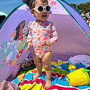 Itzel is registered to the contest to win money with this photo: barefoot, beach_tent, cartoon, child, colorful, daylight, happy, outdoor, playing, princess, purple, sand, striped_towel, summer, sunglasses, sunny, swimsuit, toddler, toy, yellow