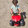 Isaac joined the competition — help win amazing prizes! child, toy, quad_bike, outdoor, dirt_road, curly_hair, red, vehicle, parked_car, shadow, sunny, play, casual_clothing, greenery, gravel, small_vehicle, young_child, daytime, concentration, hands_on_handlebars