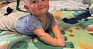 Patrick is registered to the contest to win money with this photo: baby, child, play_mat, dinosaur, alphabet, plush_toy, yellow_star, smiling, indoor, living_room, couch, baby_swing, curious, joyful, toddler, clothing, head, hands, floor, toy