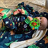 baby, infant, toy, blanket, pajamas, dinosaur_pattern, star_wars, floor, wood_floor, carpet, foot, hand, face, indoor, child, play, colorful, cute, relaxed, lying_down