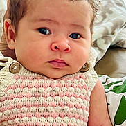 Violet is registered to the contest to win money with this photo: baby, infant, face, eyes, knitwear, clothing, hand, blanket, pillow, pattern, indoor, portrait, cute, child, person, skin, furniture, soft, texture, newborn