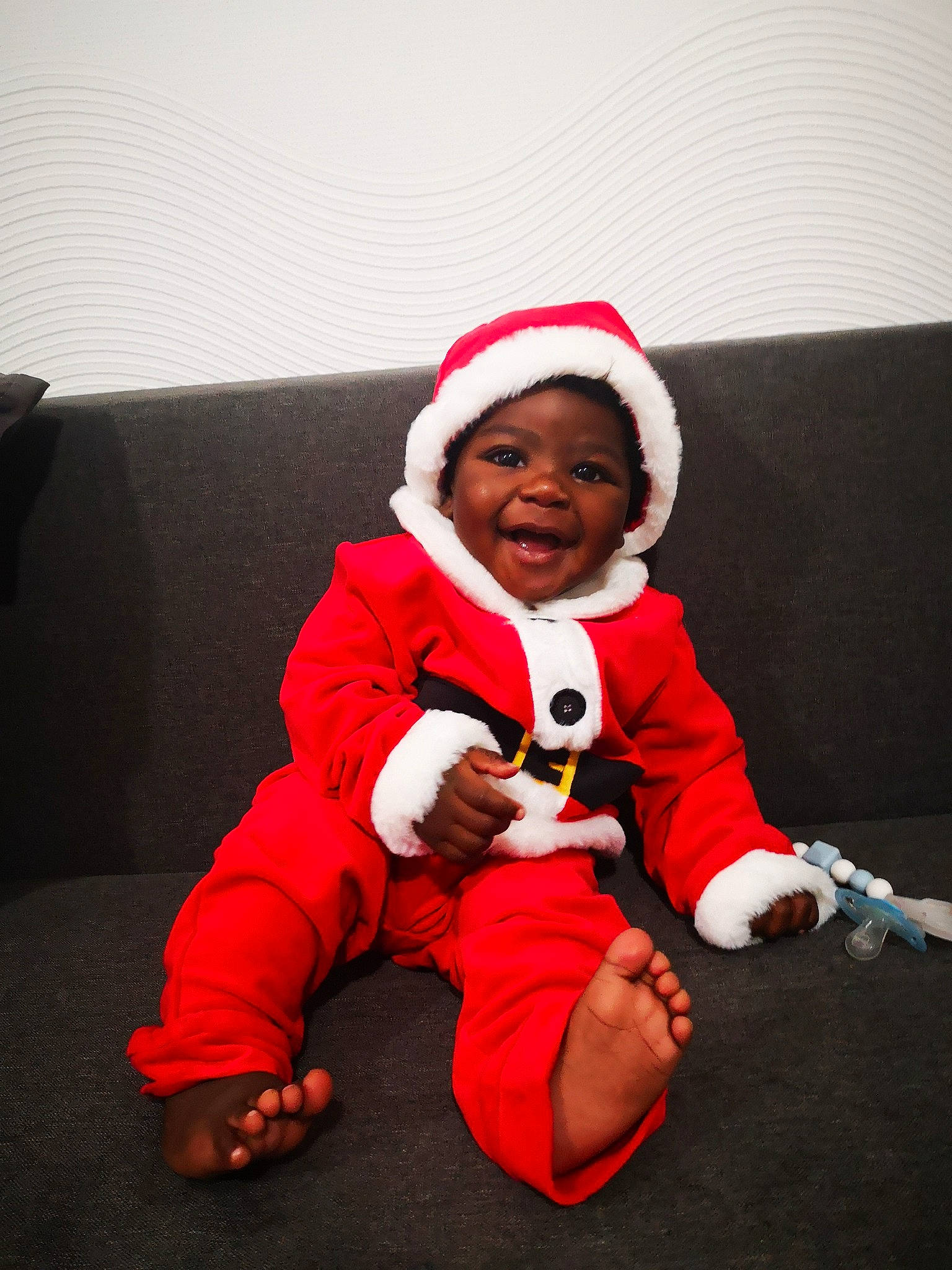 Owen participe au concours pour gagner de l'argent avec cette photo : baby, baby_toddler_clothing, cap, christmas, comfort, couch, face, flooring, gesture, happy, hat, holiday, human_body, knee, lap, person, santa_claus, sleeve, smile, toddler