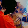 dog, pet, indoor, hug, person, orange_shirt, furniture, harness, calm, closeup, animal, companion, cute, domestic_animal, friendly, seat, curious, fur, canine, home