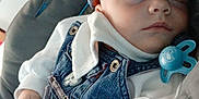 Franky participe au concours pour gagner de l'argent avec cette photo : baby, sleeping, denim_overalls, blue_cap, pacifier, cushioned_seat, infant, white_sweater, small_hands, peaceful, indoors, soft_lighting, child, cute, relaxed, closeup, portrait, baby_clothing, resting, adorable