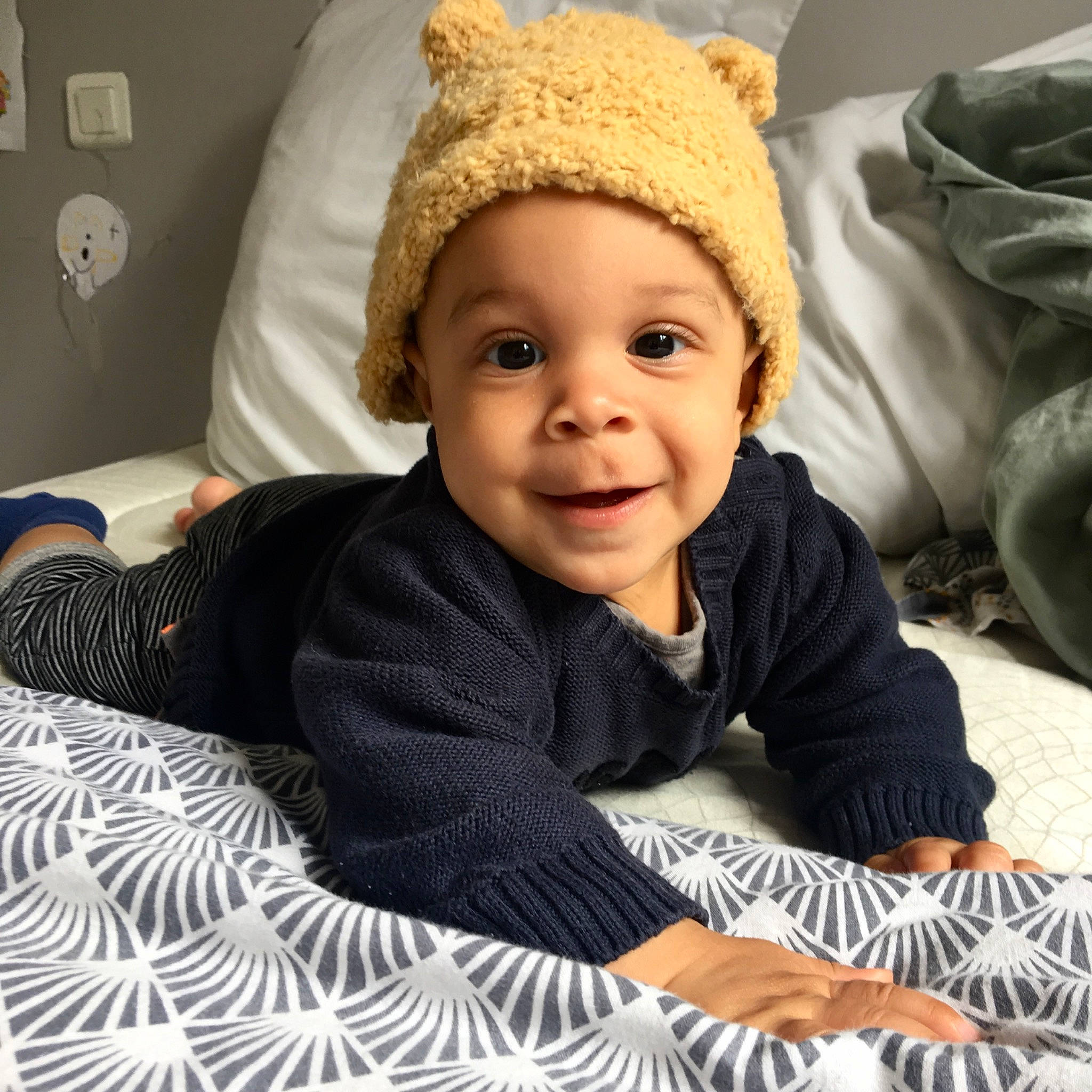 Lewis participe au concours pour gagner de l'argent avec cette photo : baby, baby_toddler_clothing, cheek, child, comfort, eye, face, facial_expression, flooring, fun, happy, headwear, joy, knit_cap, nose, person, sitting, skin, sleeve, smile