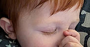Michael is registered to the contest to win money with this photo: child, baby, red_hair, sleeping, thumb_sucking, blanket, close_up, face, peaceful, soft_texture, cute, resting, indoors, person, young_child, cozy, eyelashes, hand, skin, comfort