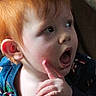 Michael is registered to the contest to win money with this photo: toddler, child, red_hair, pointing, curious, indoor, face, expression, open_mouth, person, bottle_cap, hand, young_child, clothing, head, portrait, baby, skin, sitting, furniture