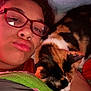person, cat, calico_cat, glasses, nose_ring, blanket, indoor, face, close_up, cute, pet, resting, cozy, snuggling, red_glasses, fur, animal, portrait, bedroom, relaxing