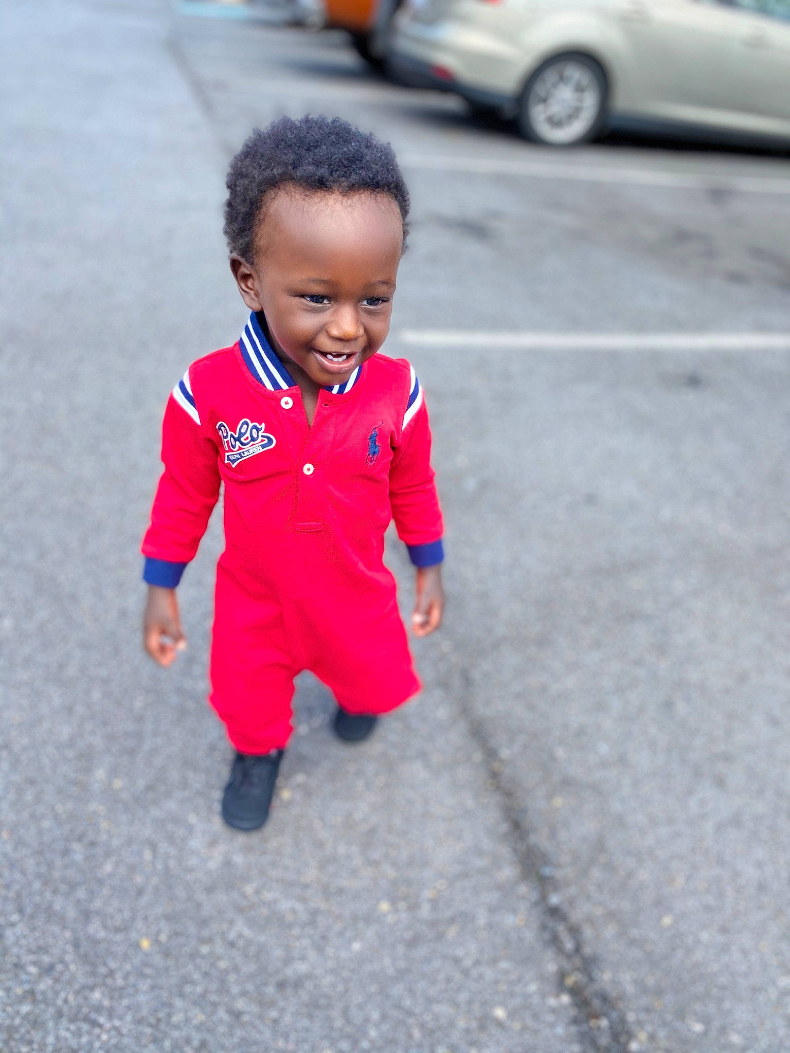 Hakeem is registered to the contest to win money with this photo: asphalt, car, child, face, facial_expression, family_car, fun, head, human, luxury_vehicle, people, person, pink, red, skin, smile, standing, street, toddler, vacation