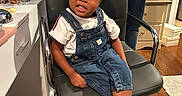 Kamani joined the competition — help win amazing prizes! toddler, child, indoor, chair, denim_overalls, boots, hair_bows, person, floor, rug, cabinet, hand, hair, smile, white_tshirt, jeans, home, furniture, adult, accessory