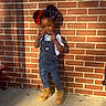 Kamani joined the competition — help win amazing prizes! child, girl, smiling, denim_overalls, boots, bows, hair, peace_sign, brick_wall, outdoor, sunlight, shadow, concrete, casual_clothing, standing, happy, playful, person, portrait, fashion