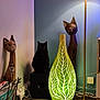 Berlingo a rejoint le concours — aidez-le/la à gagner de superbes lots ! black_cat, wooden_cat_sculpture, decorative_vase, glowing_vase, indoor, lamp, furniture, power_strip, wall, cat_eyes, shadow, quiet, cozy_corner, ornament, artistic, night_light, cables, sitting_cat, animal, home_decor