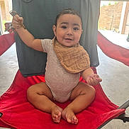 Daniel joined the competition — help win amazing prizes! baby, backyard, barefoot, bib, child, face, family_photo, folding_chair, glasses, happy, onesie, outdoor, patio, playful, portrait, red_chair, sitting, smiling, sunlight, toddler