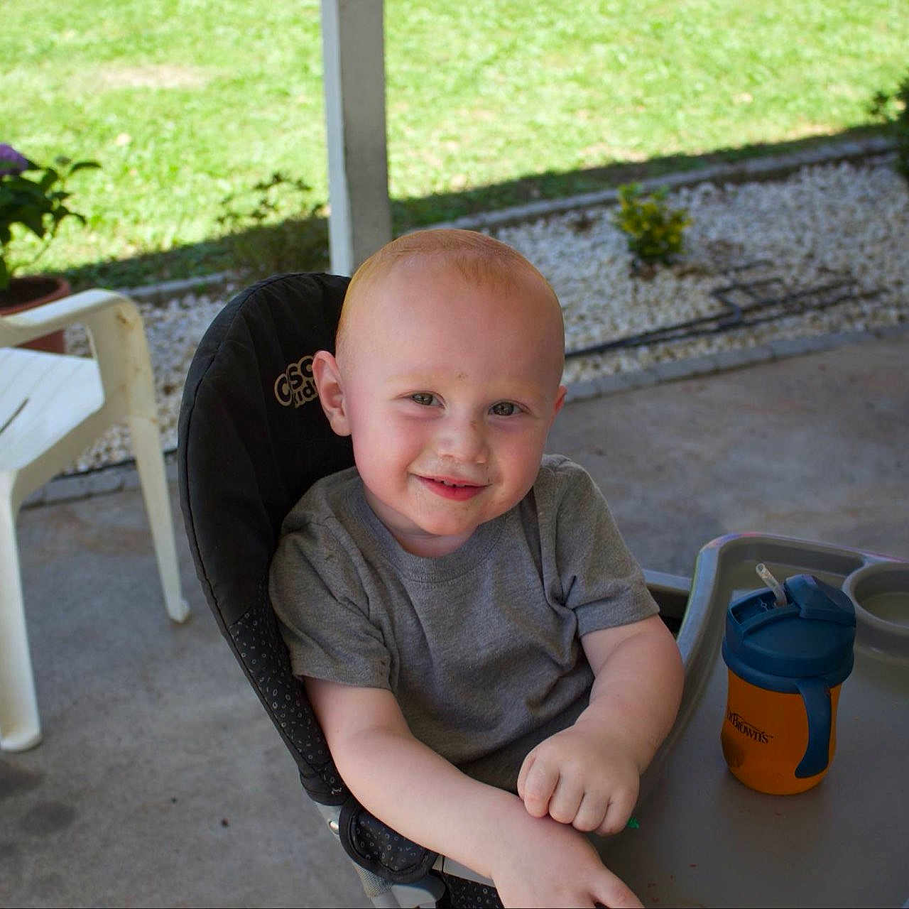 Grayson joined the competition — help win amazing prizes! baby, casual, child, concrete_floor, daylight, grass, gray_shirt, happy, high_chair, outdoor, plant, plastic_chair, porch, potted_plant, seat, short_hair, sippy_cup, smile, toddler, young_child