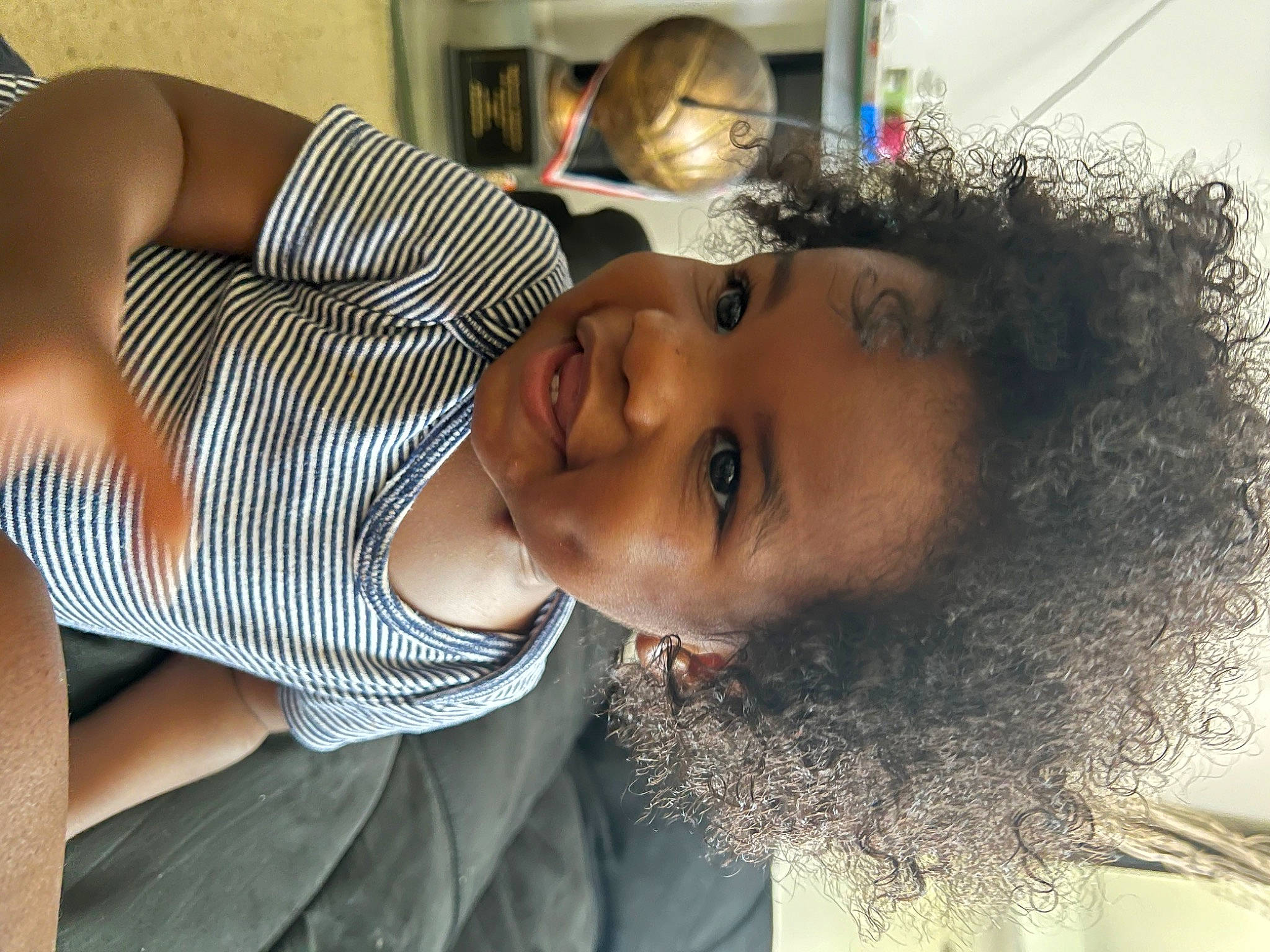 Nehemiah is registered to the contest to win money with this photo: black_hair, chin, cool, eyebrow, eyelash, facial_expression, forehead, fun, happy, lip, mouth, neck, nose, person, plant, skin, smile, toddler, tree, trunk