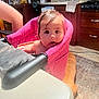 Raya joined the competition — help win amazing prizes! baby, high_chair, kitchen, dog, table, rug, television, utensils, sink, cabinet, floor, curious, wet_hair, pink, wood, countertop, appliance, person, indoor, furniture