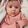 baby, child, pink_sweater, headband, bow, blanket, soft_texture, cute, portrait, indoor, infant, cozy, warm_clothing, hand, face, expression, young, adorable, close_up, curious