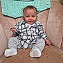baby, child, smiling, plaid_shirt, gray_pants, socks, armchair, knitted_blanket, beige, cozy, indoor, portrait, happy, person, cute, seated, home, infant, clothing, furniture