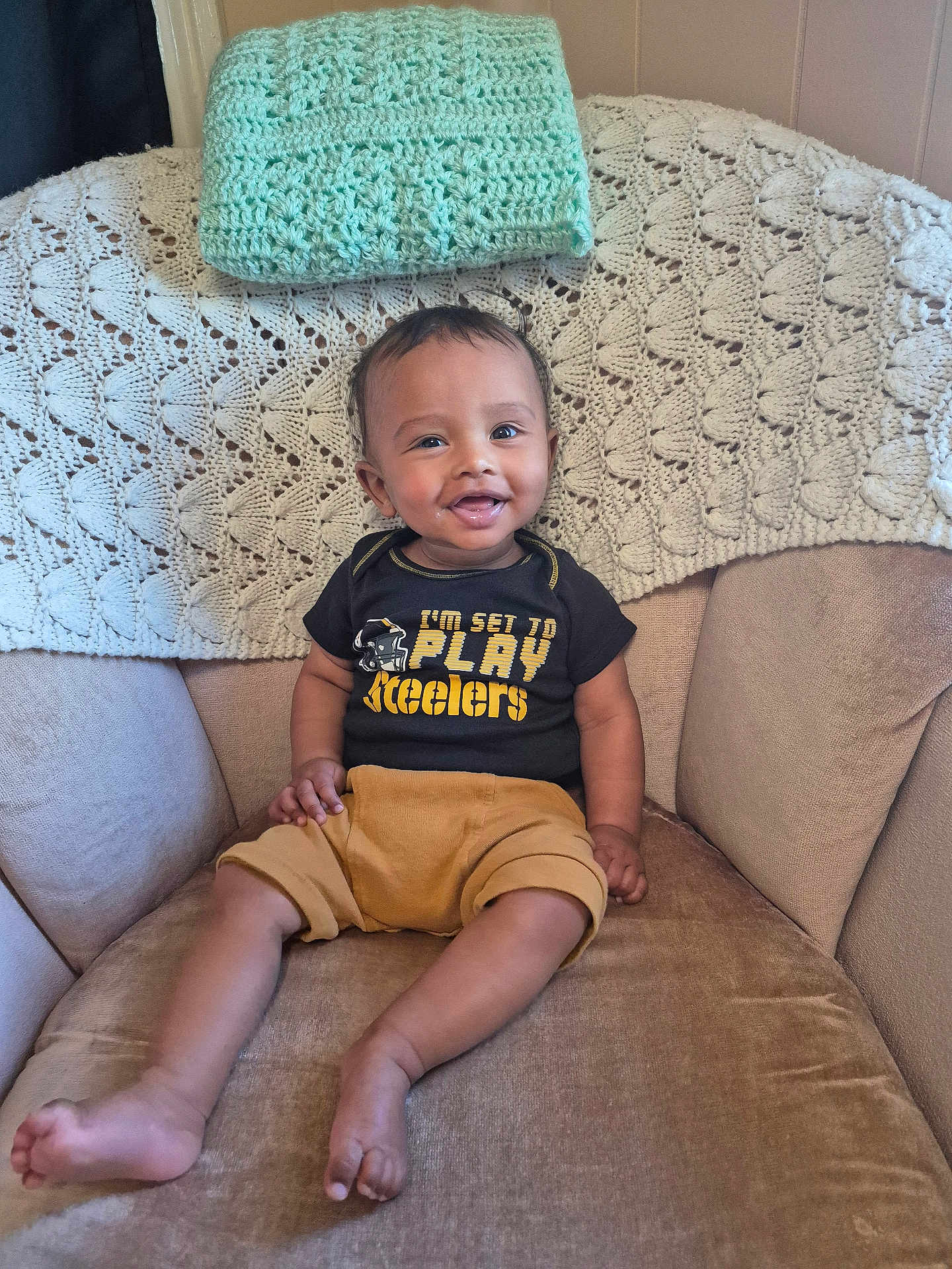 Zakariya joined the competition — help win amazing prizes! baby, child, smiling, sitting, armchair, blanket, crochet, clothing, shorts, shirt, indoor, person, face, happy, foot, hand, home, cute, infant, portrait