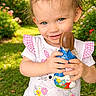 Shanna a rejoint le concours — aidez-le/la à gagner de superbes lots ! candy, child, chocolate, cute, daylight, eating, flowers, garden, grass, happy, holding, nature, outdoor, person, pink, playful, short_sleeve_shirt, smiling, toddler, white_shirt