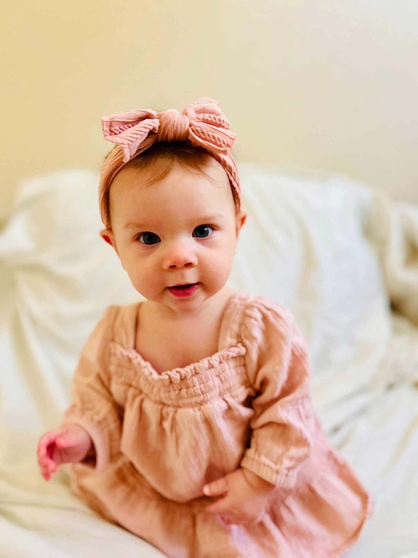 Josie is registered to the contest to win money with this photo: baby, child, girl, headband, bow, pink, dress, clothing, face, eyes, skin, hand, sitting, blanket, indoors, portrait, cute, infant, soft, young