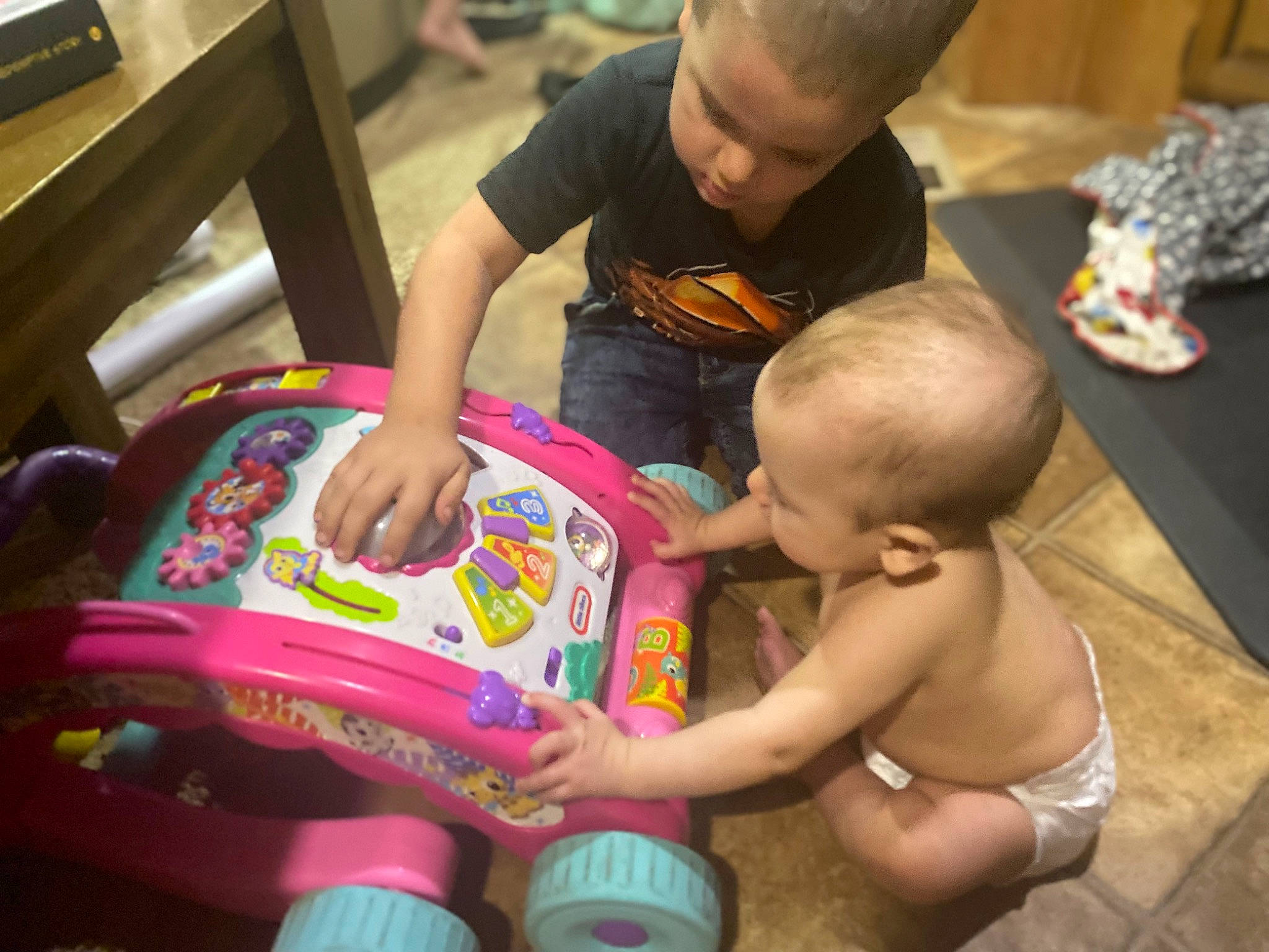 Kalianne is registered to the contest to win money with this photo: baby, baby_products, baby_toys, child, flooring, foot, fun, happy, lap, leisure, person, personal_protective_equipment, play, recreation, room, sharing, shorts, sitting, thigh, toddler