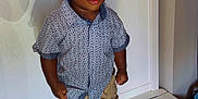 Jeremiah is registered to the contest to win money with this photo: bench, boy, casual_clothing, child, curly_hair, cute, expression, fashion, indoor, khaki_pants, patterned_shirt, person, portrait, small_child, standing, standing_pose, toddler, white_background, white_shoes, young