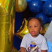 Jeremiah joined the competition — help win amazing prizes! balloons, birthday, blue_balloon, celebration, child, couch, curly_hair, cute, gold_balloon, happy, holding_shoe, indoor, number_one_balloon, party, portrait, seated, sneakers, toddler, white_tshirt, young_child