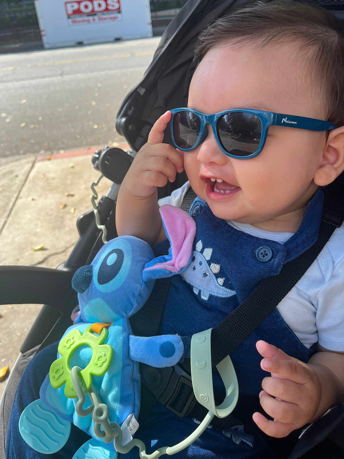 Dylan joined the competition — help win amazing prizes! toddler, child, sunglasses, smile, stroller, plush_toy, blue, outdoor, sunlight, toy, happy, baby, clothing, seatbelt, hand, face, cute, dinosaur, accessory, casual