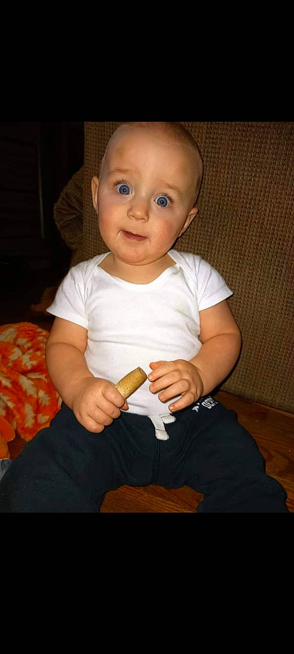 Jerry is registered to the contest to win money with this photo: baby, baby_toddler_clothing, cheek, comfort, elbow, eye, finger, flash_photography, gesture, happy, human_leg, iris, knee, nail, person, sitting, sleeve, surprise, t_shirt, thumb