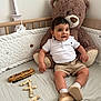 baby, bedding, celebration, child, cozy, crib, cute, eclair, happy, indoor, milestone, plush_toy, portrait, shoes, shorts, smiling, socks, teddy_bear, white_shirt, wooden_blocks