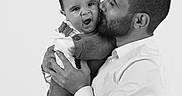 Léo a rejoint le concours — aidez-le/la à gagner de superbes lots ! affection, baby, black_and_white, chair, child, closeup, expression, family, father, holding, indoor, kiss, love, man, overalls, parent, portrait, seated, shirt, studio